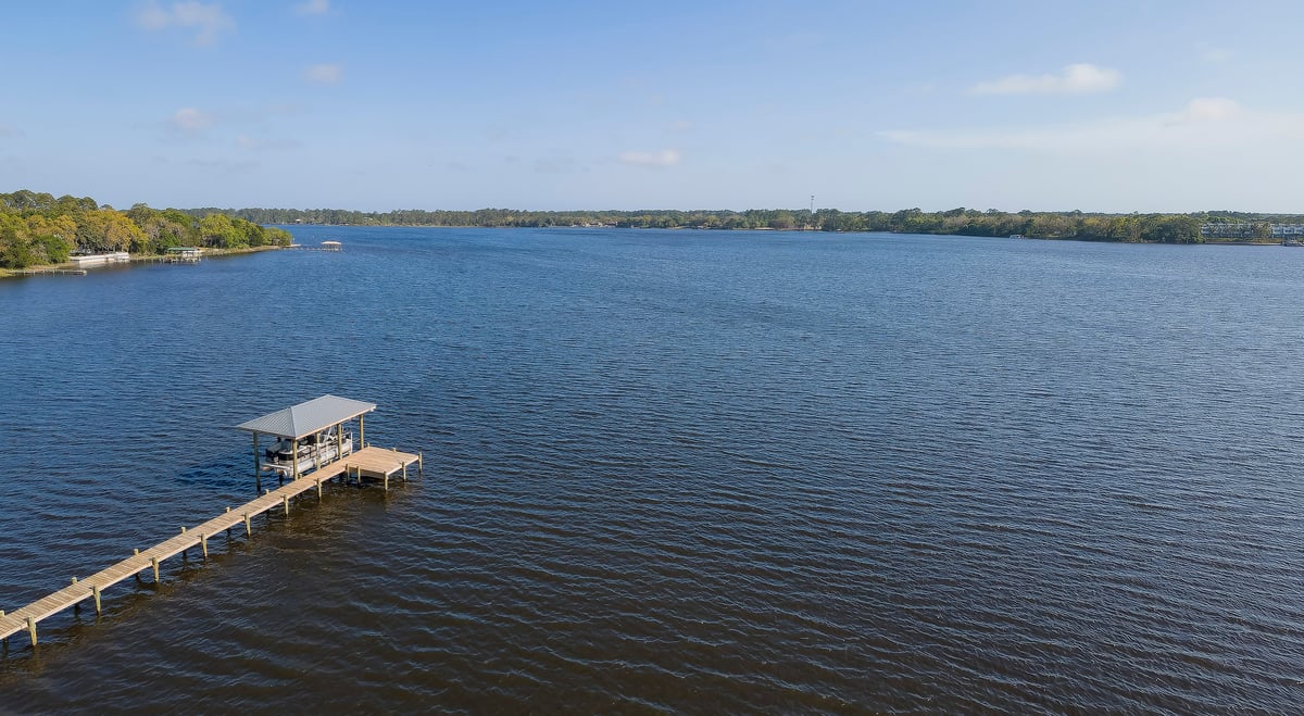 Aerial view of a private dock with covered boat lift on blue waterfront