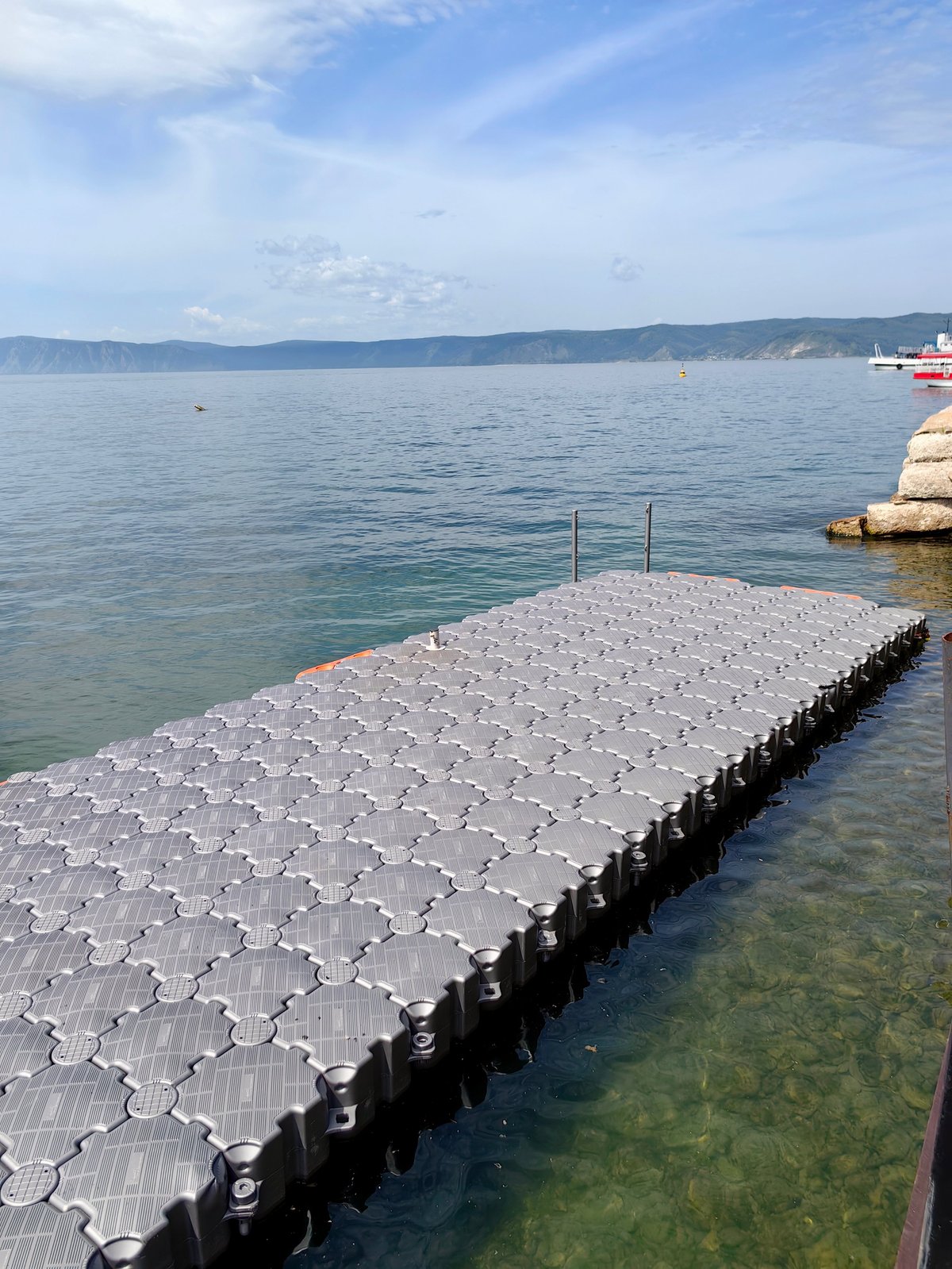 Floating dock extending into clear, serene waters with distant mountains